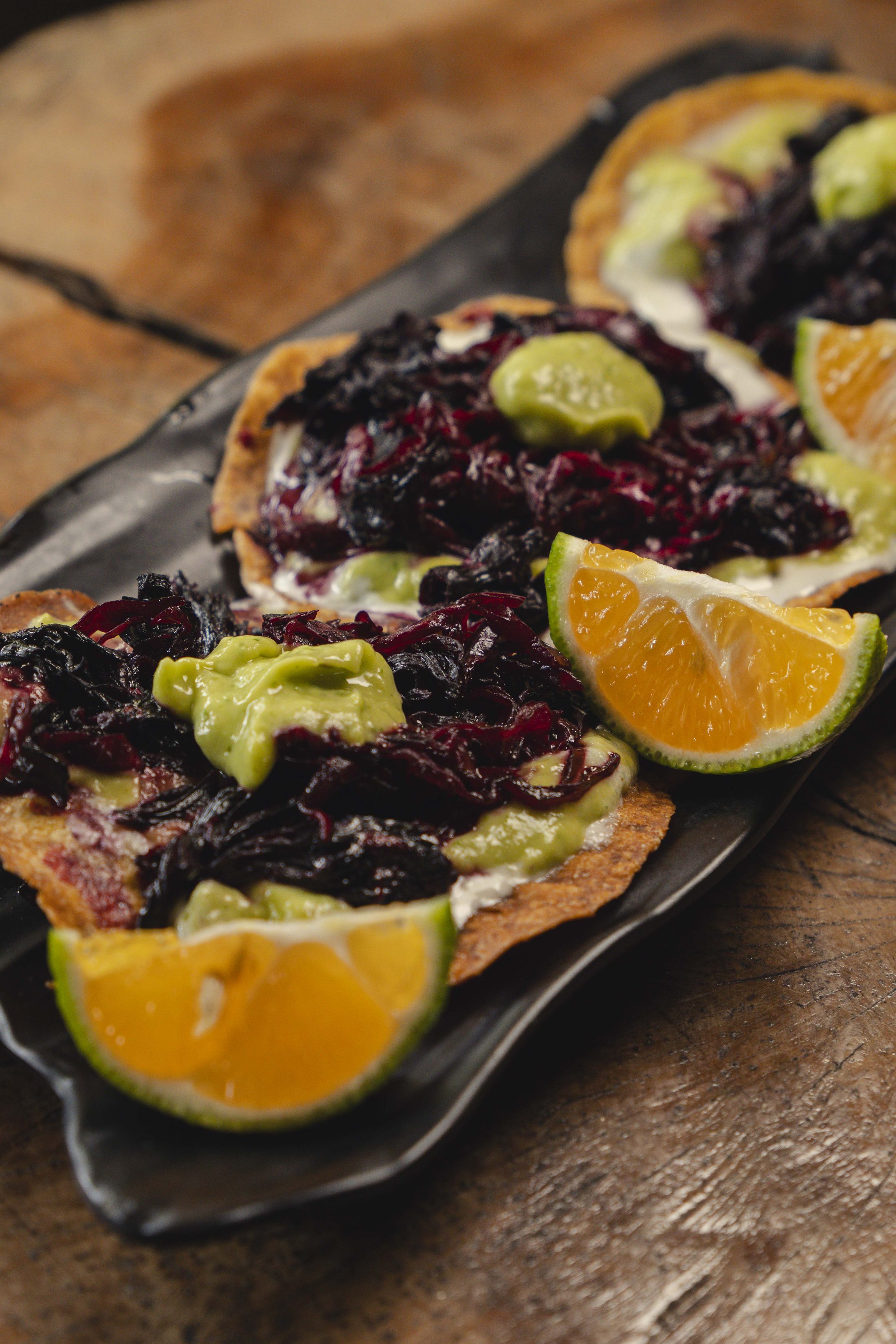 Hibiscus tostadas with avocado and citrus on dark wood